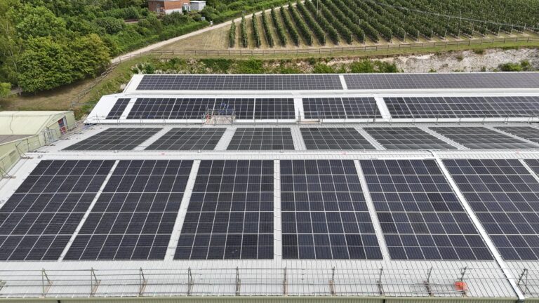 Commercial solar panel installation across multiple roof levels on an industrial building, designed to maximise energy generation from different roof orientations in the UK